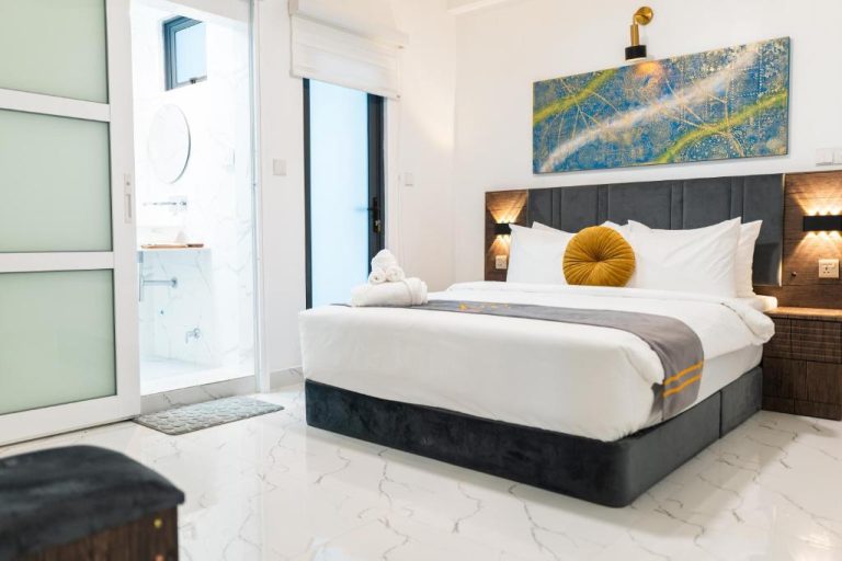 Habitación doble de lujo con cama king size y baño en suite del Aina Residency Beachfront Hotel