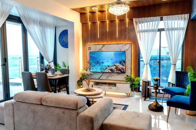 Salón moderno con televisor y vistas al mar en Aina Residency Beachfront Hotel