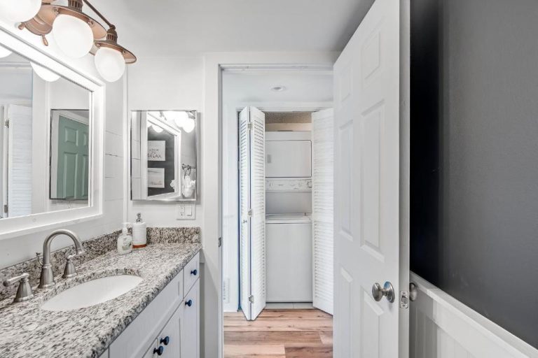 Baño con encimera de granito y lavandería integrada en el condo Pinnacle Port de Panama City Beach