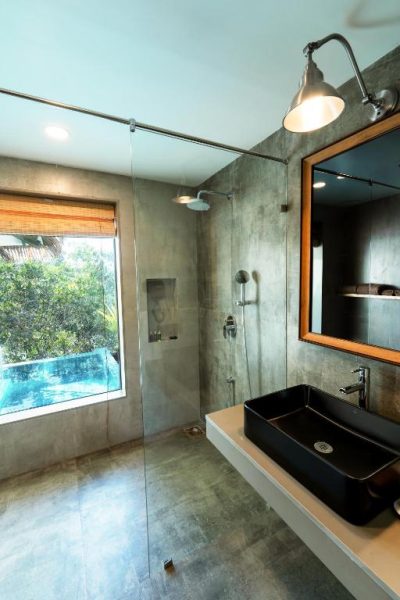 Baño moderno con ducha de lluvia y lavabo negro en el hotel SinQ Anvaya con vistas a la piscina