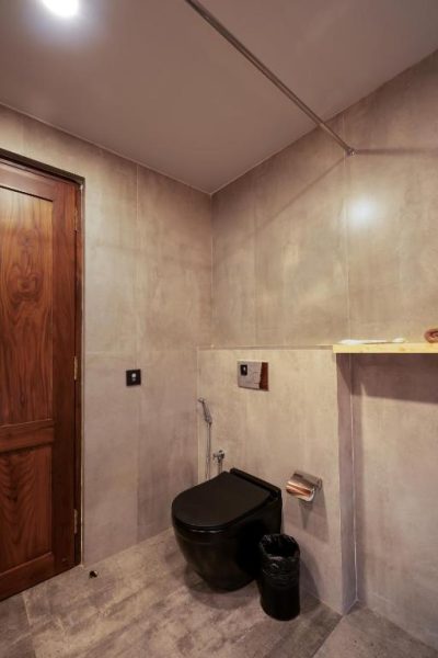 Baño moderno con inodoro negro suspendido y paredes de cemento en el hotel SinQ Anvaya