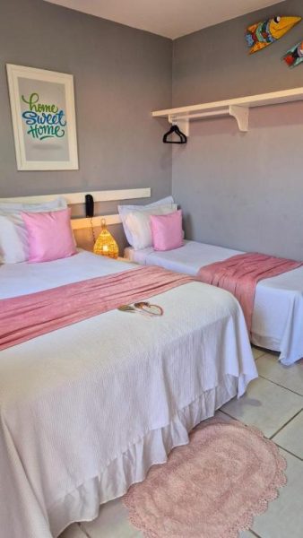 Habitación doble con camas individuales y decoración en rosa de Pousada America do Sol