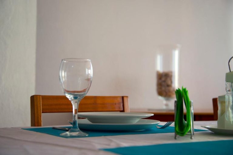 Mesa elegante del restaurante de Cacimba Sunset Lodge con vajilla blanca y copa de vino