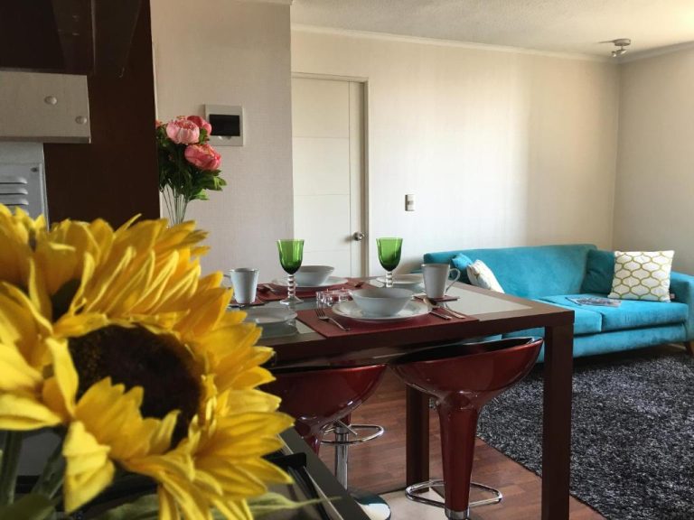 Salón comedor moderno con mesa y sofá turquesa en apartamento del hotel Azzaí Bellas Artes