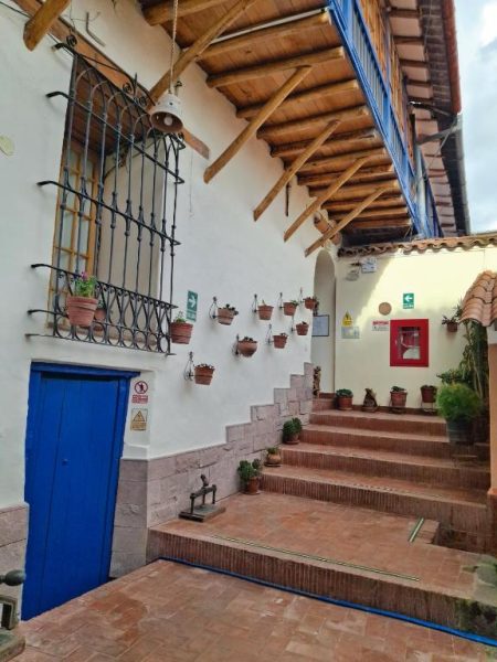 Patio interior con escaleras de ladrillo y macetas en la pared de Casona La Recoleta en Cusco