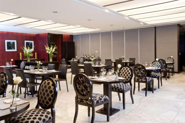 Restaurante elegante del NH Buenos Aires Tango con mesas preparadas y sillas tapizadas en blanco y negro