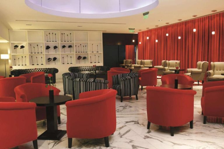 Lobby bar del NH Buenos Aires Tango con sillones rojos, cortinas carmesí y decoración de sombreros