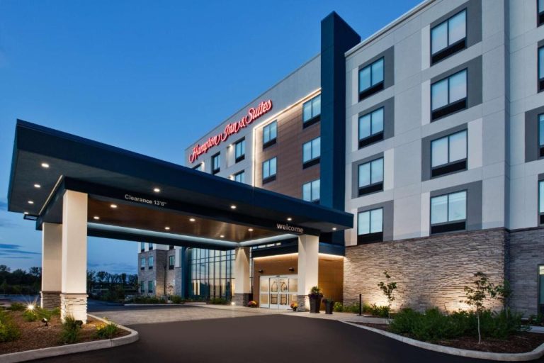 Fachada exterior e ingreso principal iluminado del Hampton Inn & Suites Indianapolis South Greenwood al anochecer