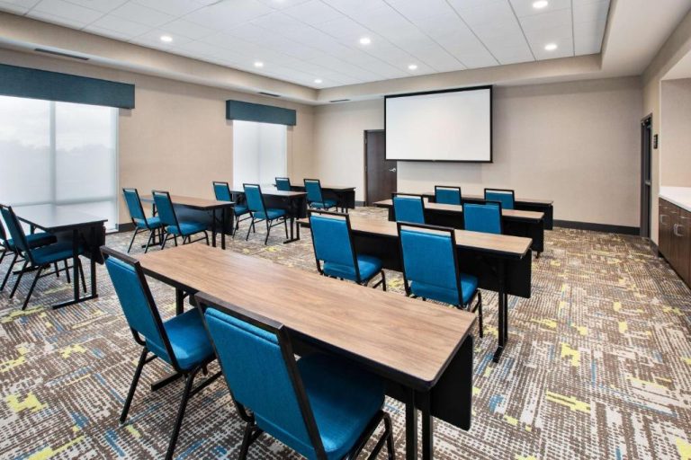 Sala de reuniones con sillas azules, mesas y pantalla de proyección en Hampton Inn Indianapolis South Greenwood