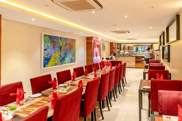 Restaurante elegante con sillas rojas y arte moderno en The Somerset Hotel, perfecto para cenas y eventos