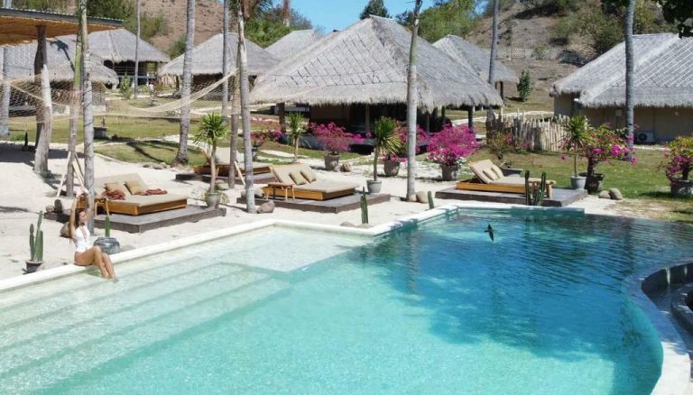 Piscina exterior con tumbonas y bungalows de techo de paja en Bleu Mathis Gili Asahan