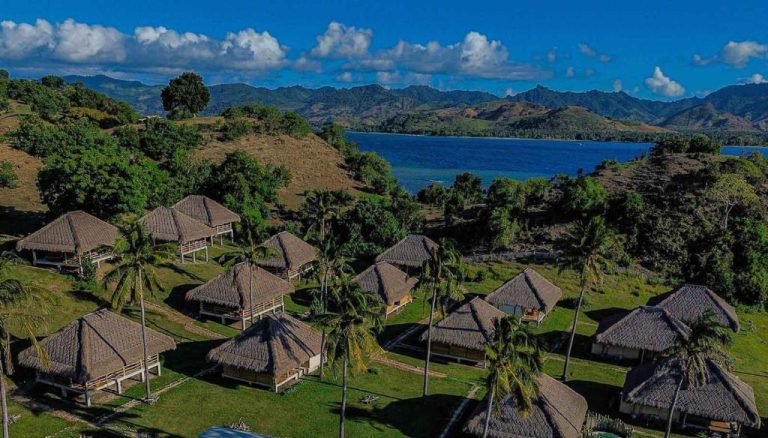Vista aérea de las villas con techo de paja del Bleu Mathis Gili Asahan rodeadas de palmeras y mar