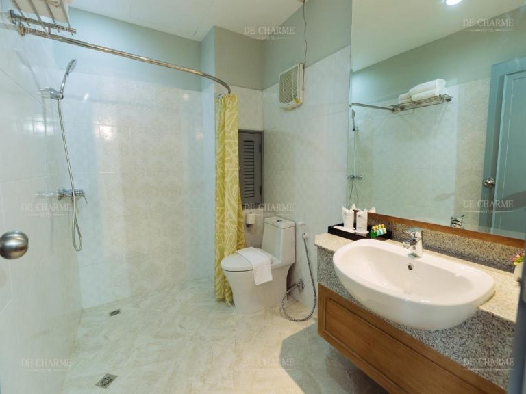 Baño completo con ducha, inodoro y lavabo de mármol blanco en el Decharme Hotel
