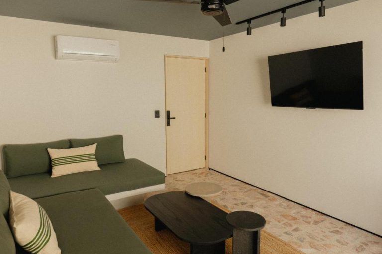 Sala de estar con sofá verde y televisor en pared del Ixum Casa Hotel Boutique