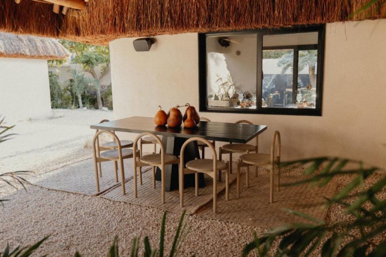 Terraza comedor exterior con techo de palapa y mesa oscura en Ixum Casa Hotel Boutique
