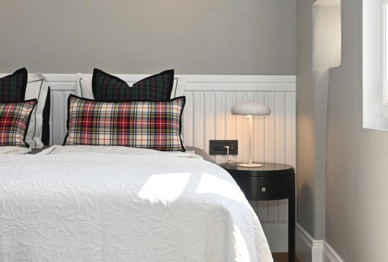 Habitación con cama doble, ropa blanca y cojines de cuadros escoceses en MILIN DOM Premium Apartments