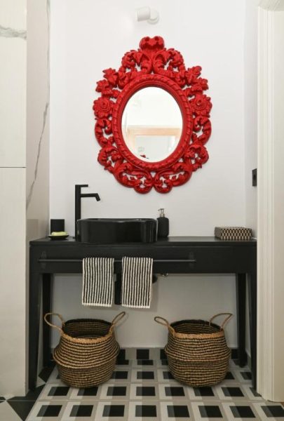 Baño elegante con espejo barroco rojo y lavabo negro en MILIN DOM Premium Apartments