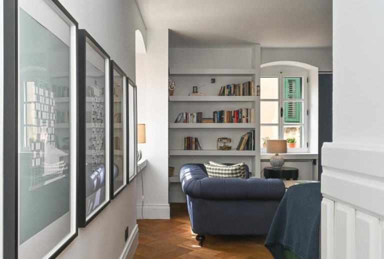 Salón con sofá azul Chesterfield y estantería de libros en MILIN DOM Premium Apartments