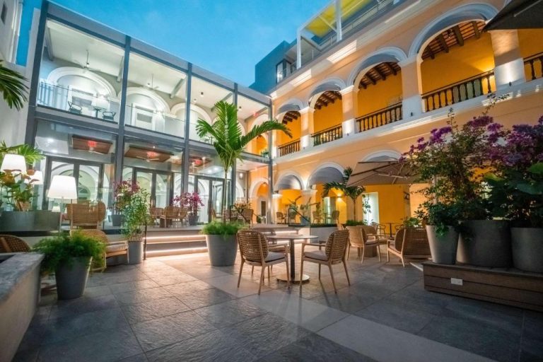 Elegante patio terraza con mesas y vegetación tropical del Palacio Provincial San Juan Curio Collection by Hilton
