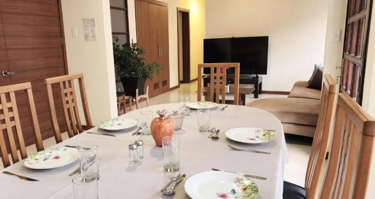 Comedor elegante con mesa para seis personas y salón con televisor en Altamira Apart Suites