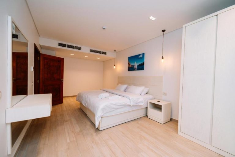 Habitación doble moderna con cama blanca y suelo de madera clara en Zones Residence Maadi