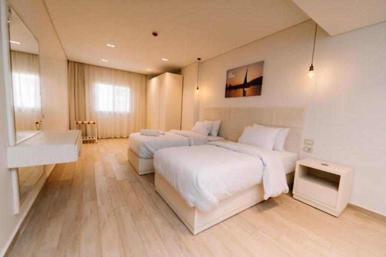 Habitación doble luminosa con dos camas y decoración blanca en Zones Residence Maadi