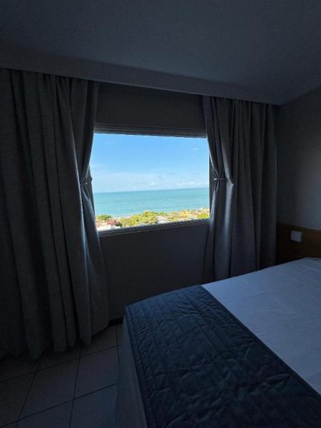 Habitación con cama doble y ventana con vista panorámica al mar en Flat Vista Mar Ponta Negra Natal