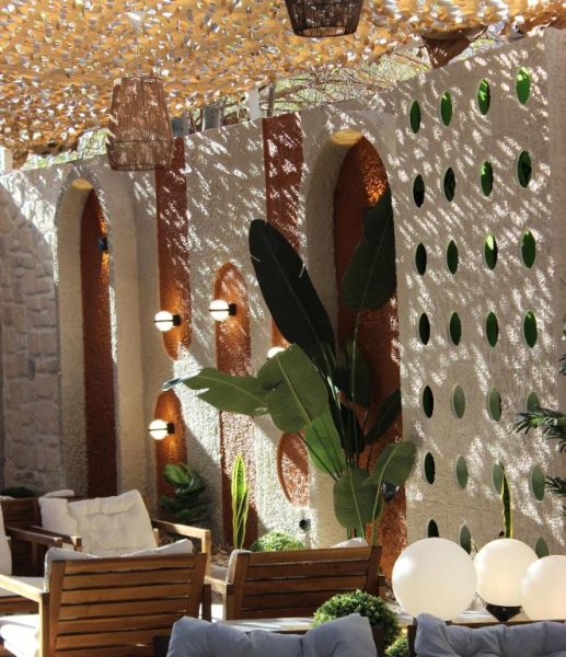 Terraza exterior del Bonnie City Hotel con mobiliario de madera, plantas tropicales y decoración mediterránea con arcos
