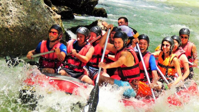 Grupo de personas practicando rafting en aguas bravas cerca del Bonnie City Hotel con chalecos salvavidas