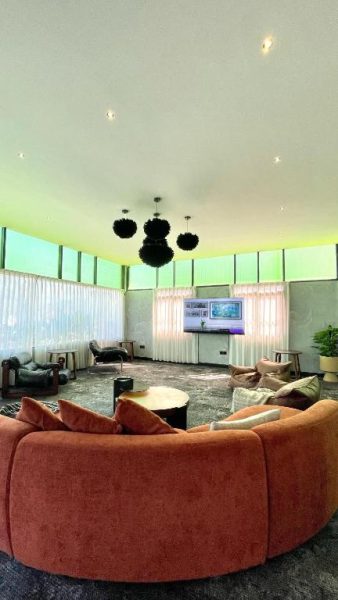 Sala de estar con sofá circular naranja y pantalla TV en BaBa Boutique House Langkawi