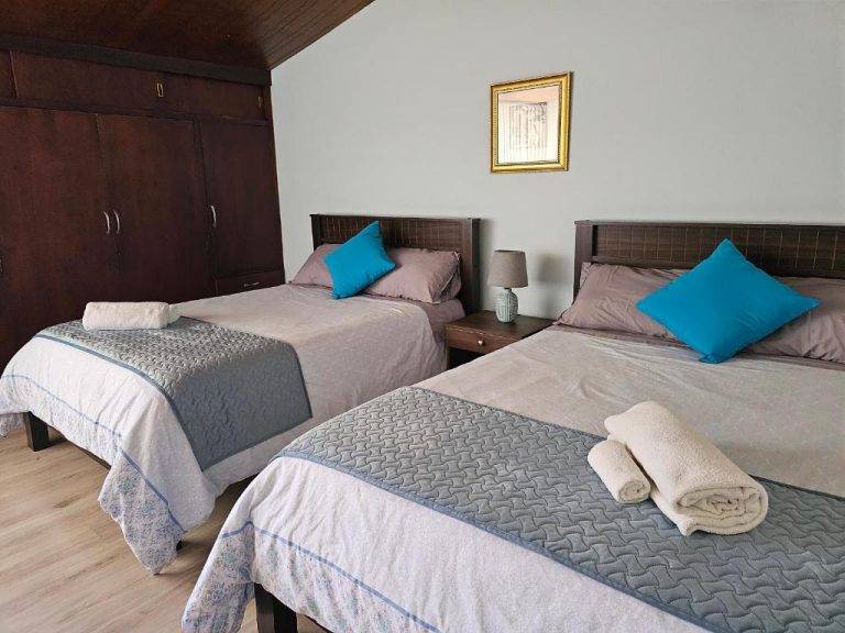 Habitación triple con tres camas individuales y cojines azules en Altamira Apart Suites