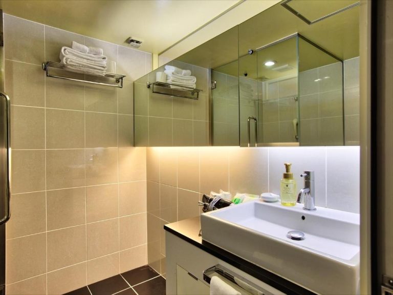 Baño moderno con lavabo blanco, amenities y cabina de ducha en el Palace In Moon Beach