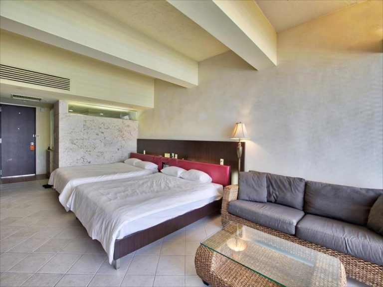 Habitación doble con cama grande, sofá de ratán y lámpara de pie en Palace In Moon Beach