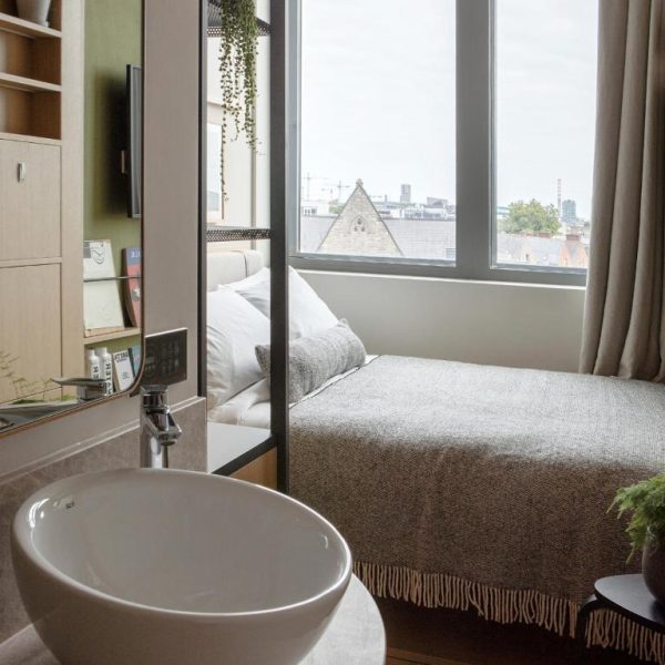 Habitación moderna con lavabo y cama junto a ventana con vistas a la ciudad en Wren Urban Nest
