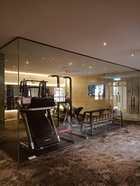 Gimnasio moderno con paredes de cristal y equipos de pesas en BaBa Boutique House Langkawi