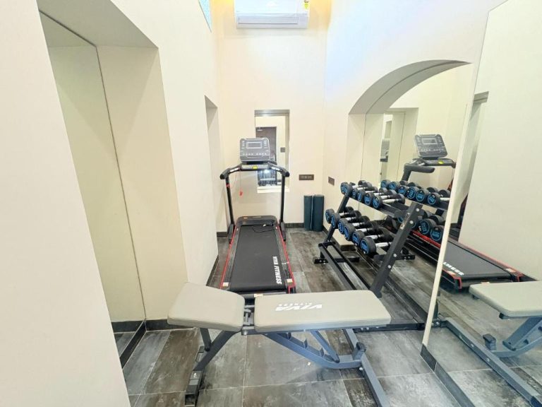 Gimnasio con cinta de correr, mancuernas y banco de pesas en Saltstayz Autograph Connaught Place