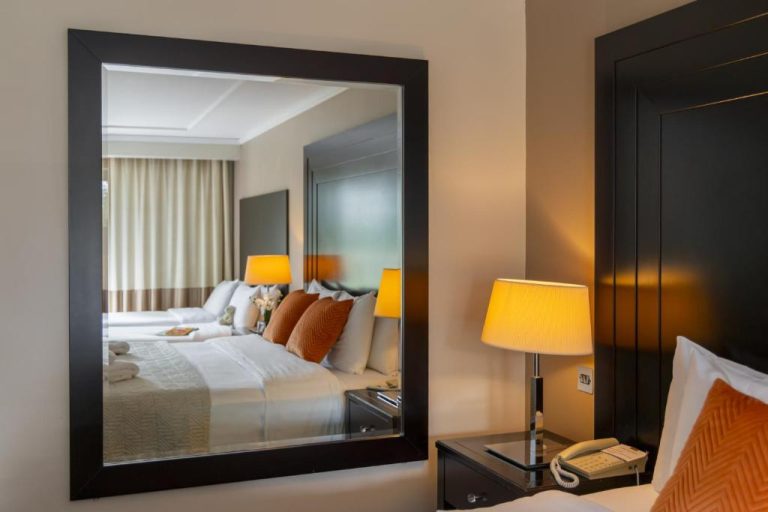 Habitación doble elegante con espejo decorativo y lámpara en Shamrock Lodge Hotel