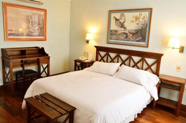 Habitación doble con cama king size y mobiliario de madera clásico en Hotel Santa Cristina
