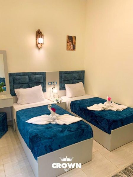 Habitación doble con camas vestidas en azul y decoración de toallas en forma de cisne en Crown Hotel