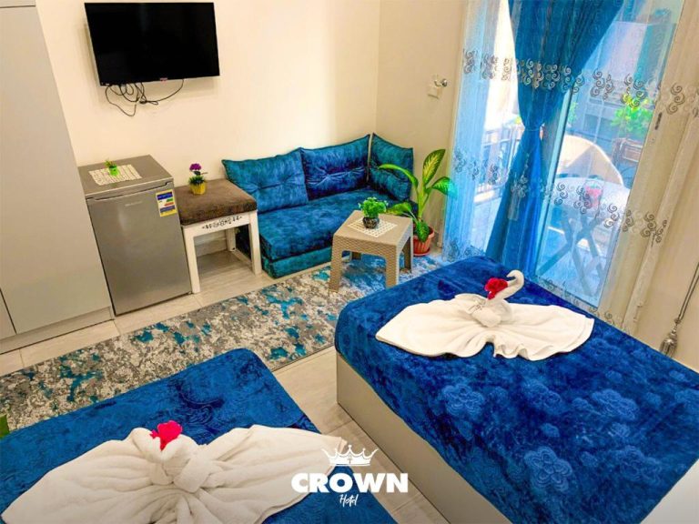 Habitación doble con camas azules, sofá y balcón en Crown Home Hotel