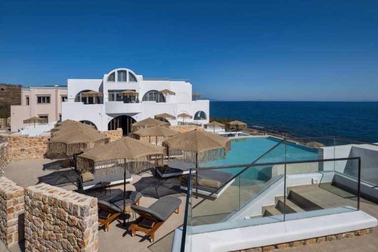 Piscina exterior con tumbonas y sombrillas de palapa del hotel Aelia Thalassa frente al mar Egeo