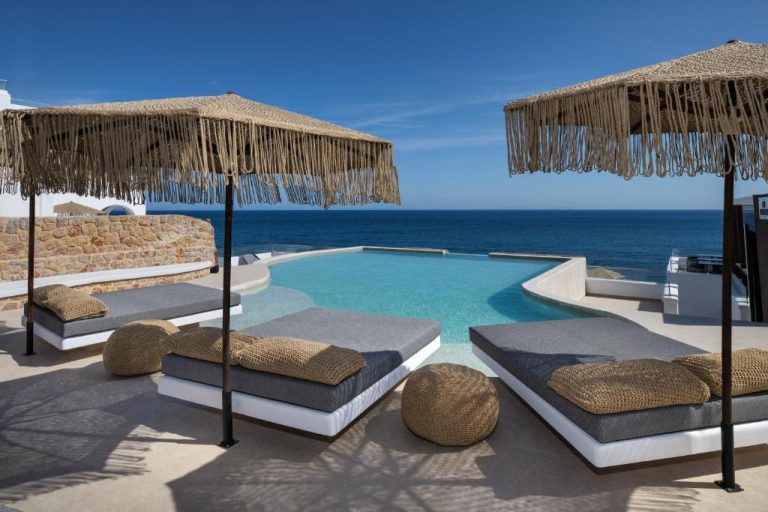 Piscina infinita con tumbonas y sombrillas de fibra natural en Aelia Thalassa con vistas al mar Egeo