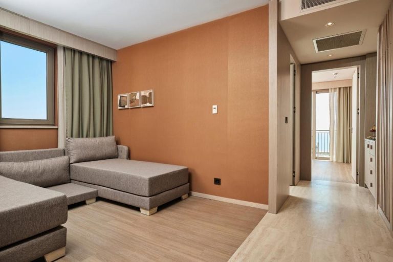Salón de suite en Lusso Sorgun con sofá chaise longue gris y paredes en tonos terracota