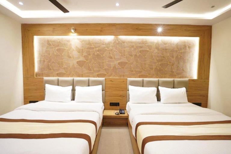 Habitación doble con dos camas y elegante cabecero de madera iluminado en Hotel Lancaster