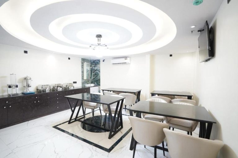 Salón de desayunos moderno con mesas negras y sillas beige en el Hotel Lancaster
