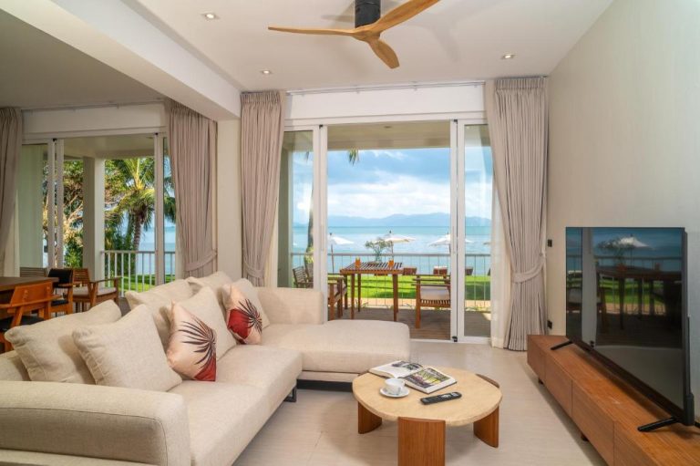 Salón con sofá blanco y vistas al mar desde terraza en Baan Bophut Beach Hotel Samui
