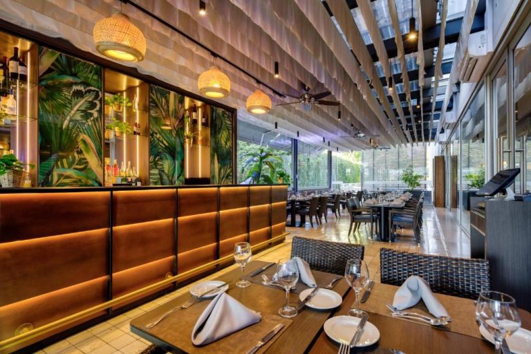 Restaurante interior del Radisson Blu Plaza El Bosque Santiago con bar tropical y mesas elegantemente servidas