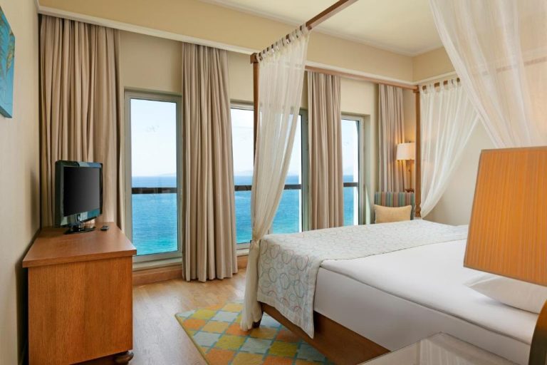 Habitación doble con cama con dosel y vistas al mar turquesa en el hotel Xanadu Island