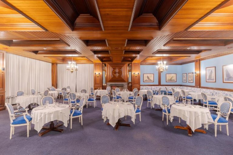 Elegante salón comedor del Pestana Bahia Praia Nature & Beach Resort con mesas blancas y sillas azules