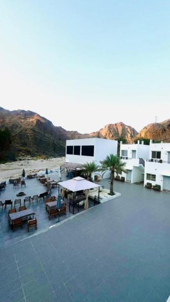 Terraza exterior con mesas y sillas del Wadi Al Arbeieen Resort rodeado de montañas rocosas